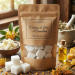 Sachet kraft de « Cristaux de fleur d'Osmanthus » entouré d'ingrédients naturels (fleurs jaunes, beurre de karité et huile) sur une table en bois.