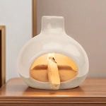 Un brûleur d'encens en céramique avec collecteur de cendres posé sur une table en bois, en fonctionnement avec un baton de palo santo allumé dedans