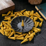 un cône d'encens au jasmin dans un bruloir entouré de plusieurs cônes d'encens au jasmin