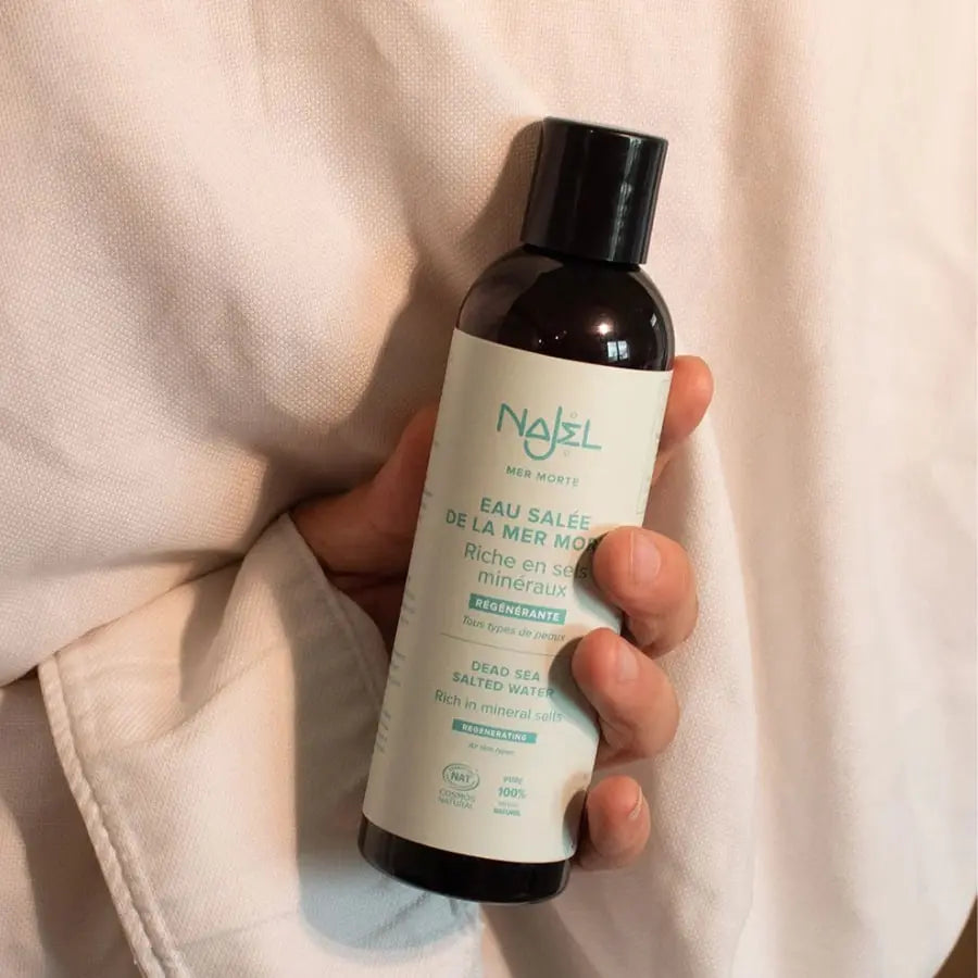 Un flacon de 200 ml d'eau Salée de la Mer Morte Najel tenu en main