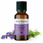Un flacon de 50ml d'huile essentielle de Lavande vraie de la distillerie Saint-Hilaire accompagné de lavandes en arrière plan.