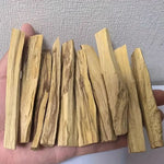 Une main tenant 10 bâtons de palo santo