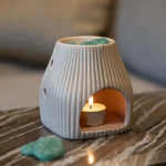 Un bruleur de fondants parfumés de la marque Scentchips posé sur une table en marbre, avec une bougie chauffre-plat allumée à l'intérieur