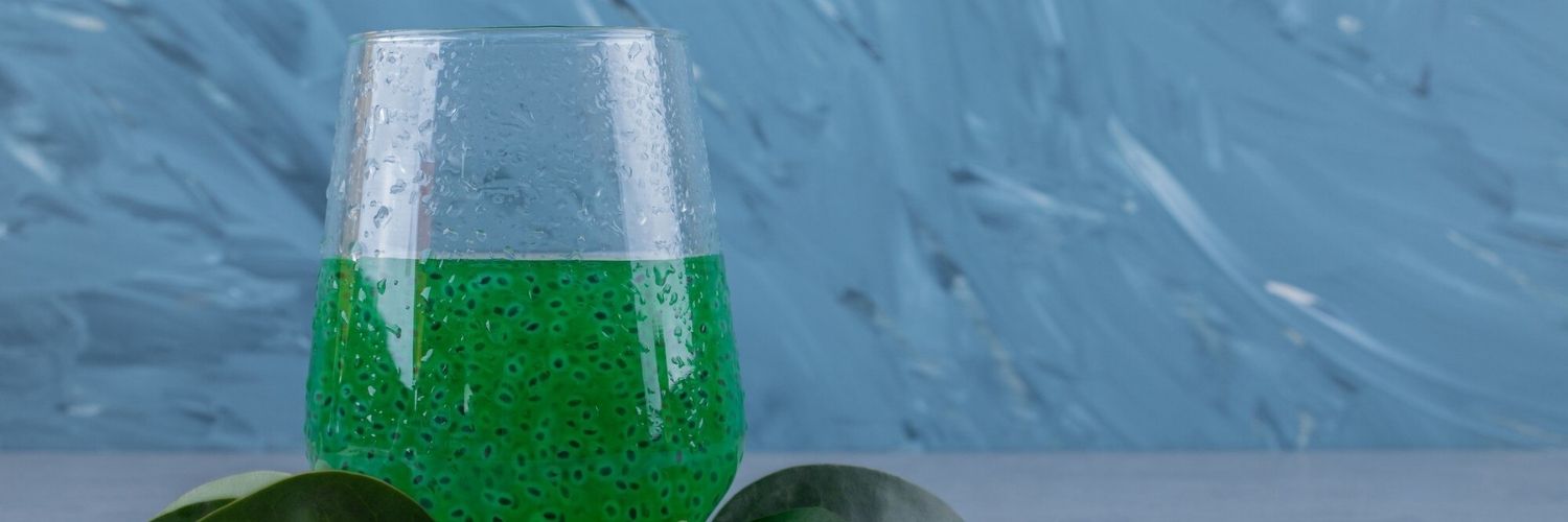 Un verre de spiruline sur un fond bleu. 