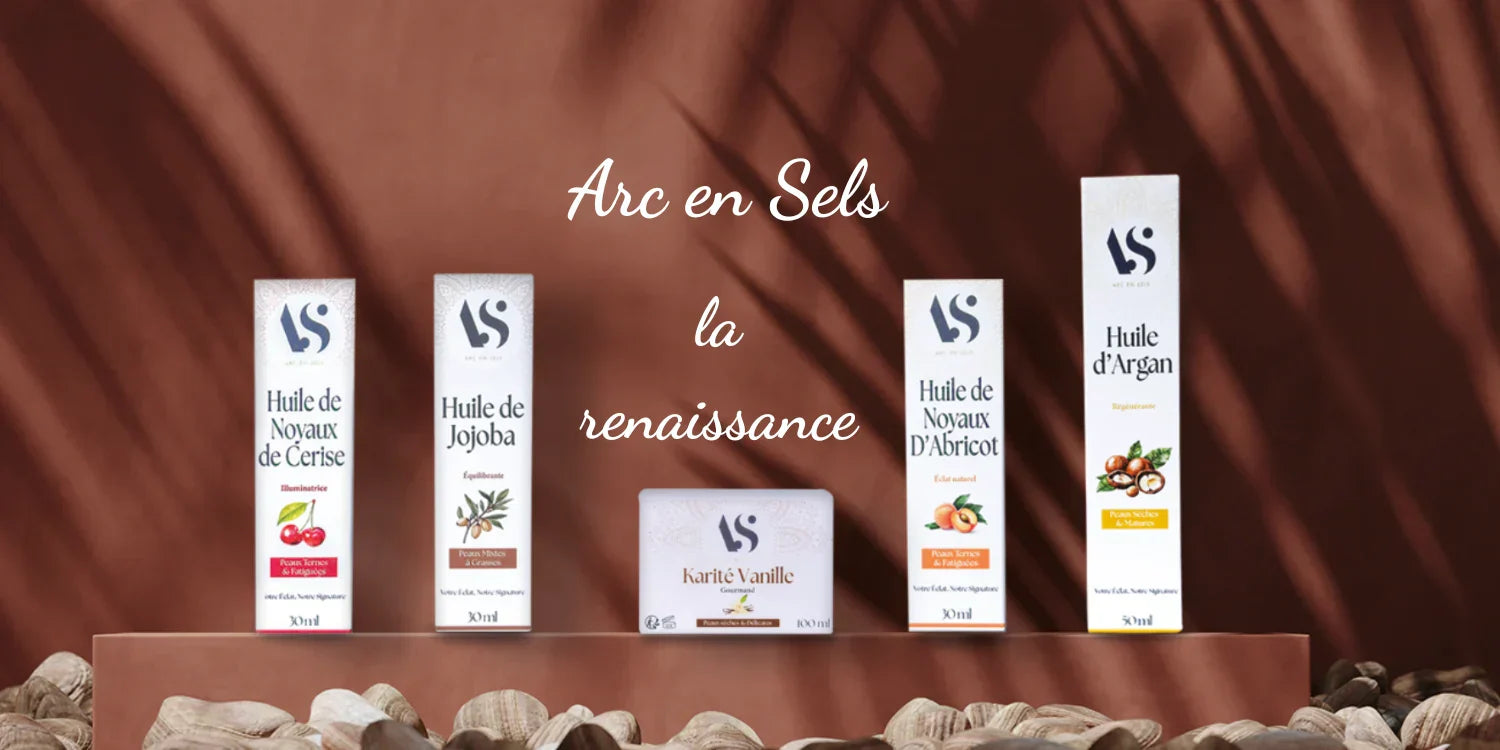 5 produits Arc en Sels alignés devant un mur en terre cuite, avec des ombres de feuilles