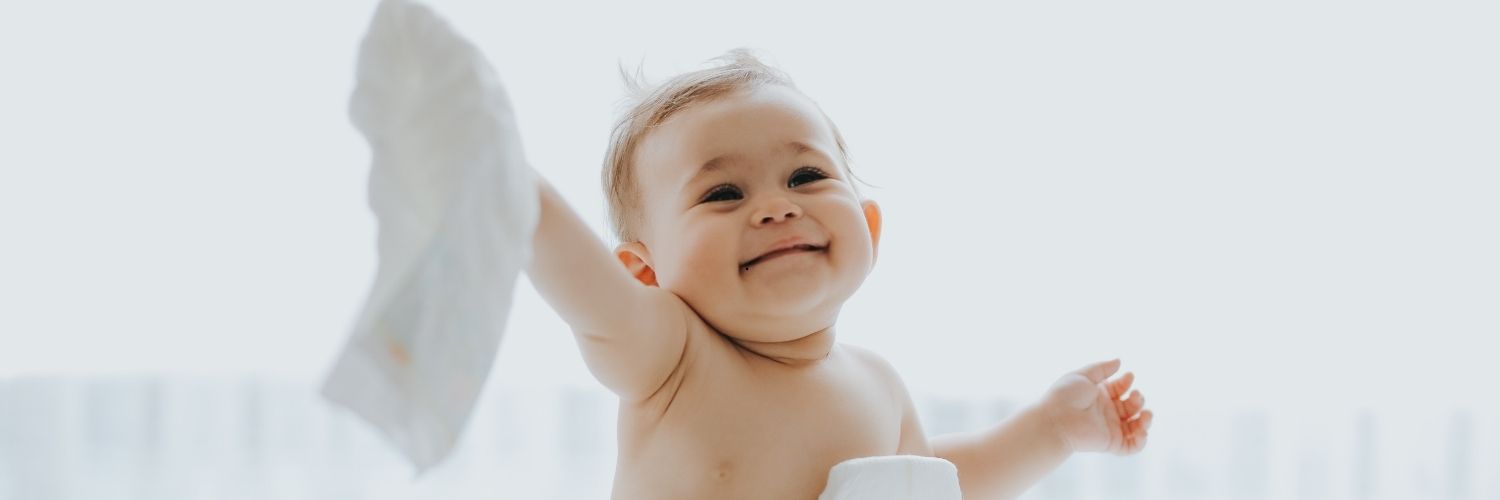 Un bébé heureux et souriant tenant une couche dans sa main droite