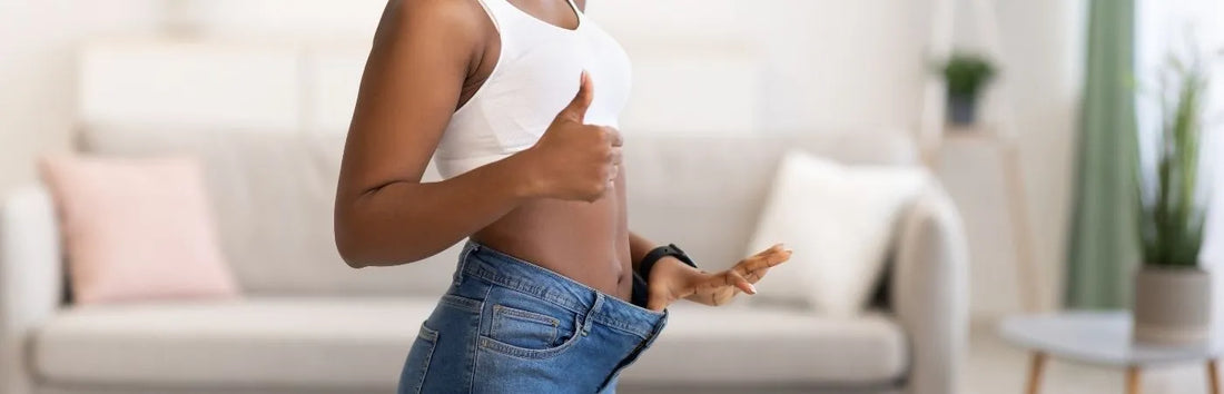 Photo d'une femme nous montrant que son jean est trop grand car elle a visiblement perdu du poids. Elle affirme son bonheur avec un pouce en l'air.