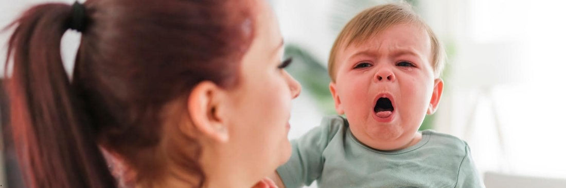 Photo d'un bébé en train de tousser, tenu à bras par sa maman