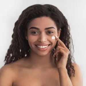 Femme souriante à la peau lumineuse touchant sa joue