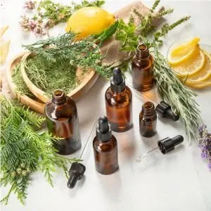 Flacons d'huiles essentielles entourés de plantes aromatiques, d'agrumes et de lavande