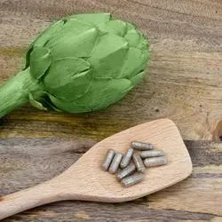 Artichaut et gélules posées sur une cuillère en bois