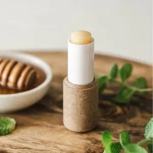 Stick de baume à lèvres naturel posé sur un support en bois, avec du miel