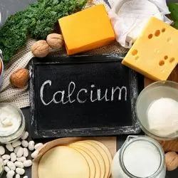 Ardoise « Calcium » entourée de fromages, lait, brocoli et fruits à coque