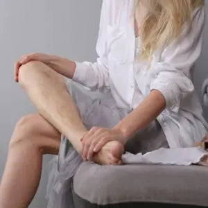 Femme assise se massant les jambes pour soulager la sensation de jambes lourdes