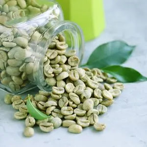 Grains de café vert renversés d'un bocal en verre, avec des feuilles fraîches