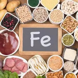 Symbole Fe entouré d'aliments riches en fer : viandes, légumineuses, noix et graines