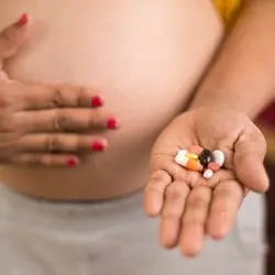 Femme enceinte tenant des gélules de compléments alimentaires devant son ventre