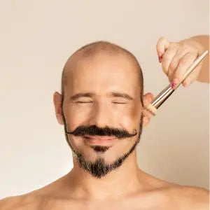 Homme barbu souriant se faisant tailler la moustache aux ciseaux