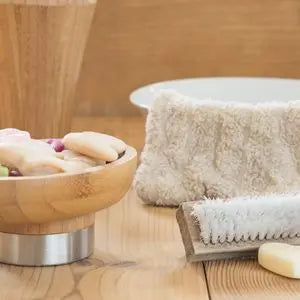 Savons naturels, brosse en bois et gant de toilette en coton dans une salle de bain