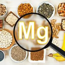 Loupe sur le symbole Mg entourée de graines, noix, légumineuses et céréales riches en magnésium