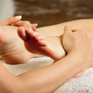 Mains massant un pied pendant un soin des pieds
