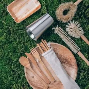 Accessoires zéro déchet en bambou et gourde en inox posés sur l'herbe