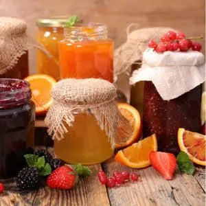 Pots de miel et de confitures entourés de fruits frais