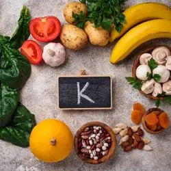 Ardoise « K » entourée de bananes, pommes de terre, tomates et fruits secs riches en potassium