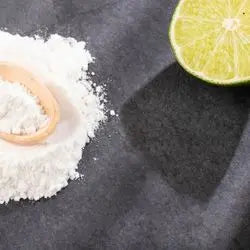 Tas de sel blanc et cuillère en bois à côté d'un demi-citron vert