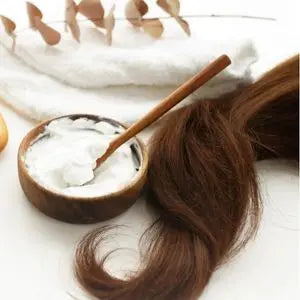 Longue mèche de cheveux bruns à côté d'un bol de masque capillaire