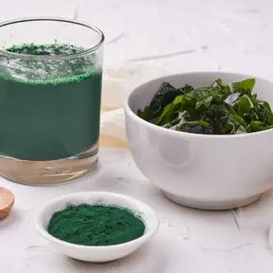 Verre de jus vert, bol d'algues et coupelle de spiruline en poudre