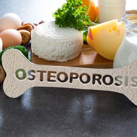 Une photo avec au premier plan un os sur lequel est inscrit le mot "ostéoporose"