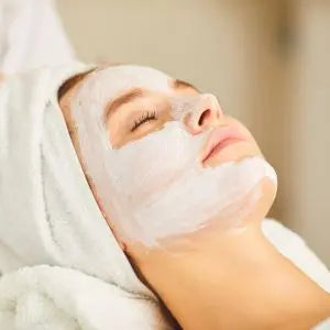 Femme allongée et détendue avec un masque de soin blanc sur le visage