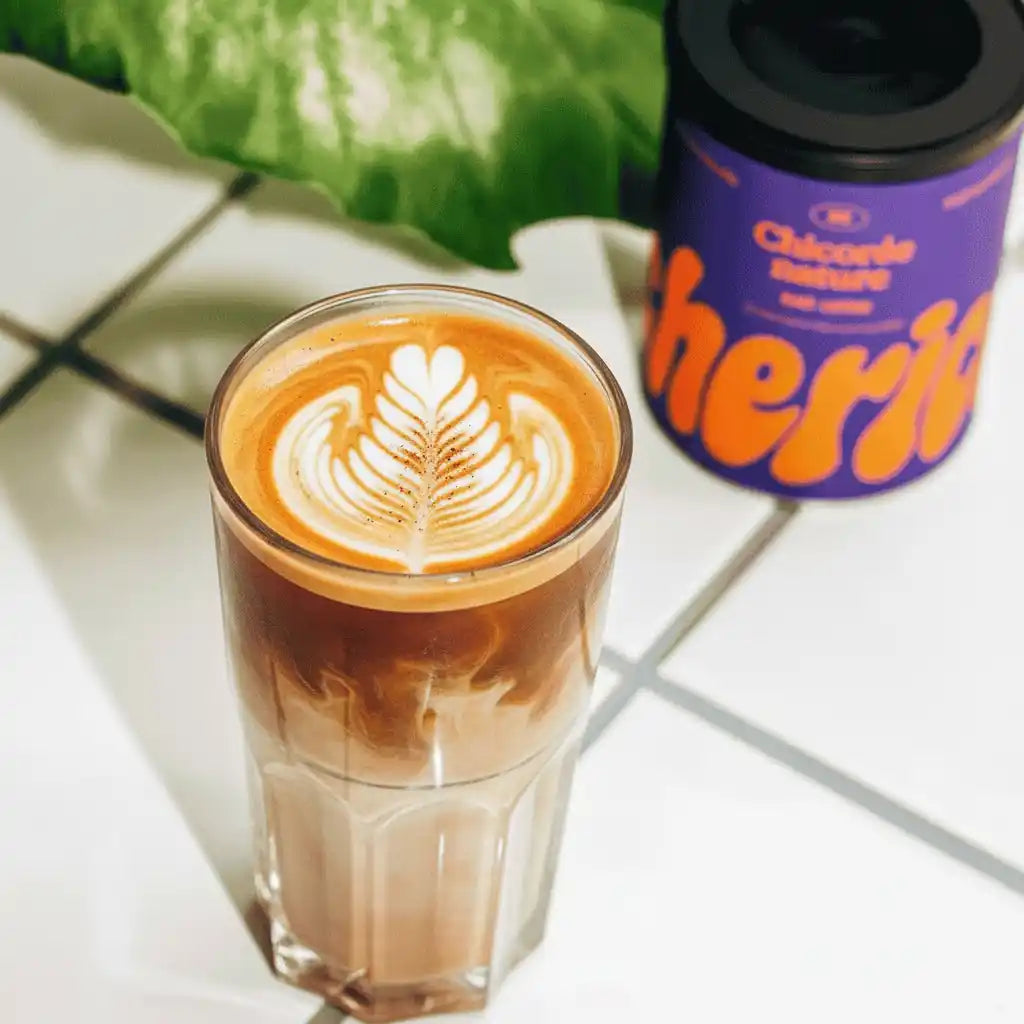 Un verre de chicorée avec du lait sur du carrelage blanc.