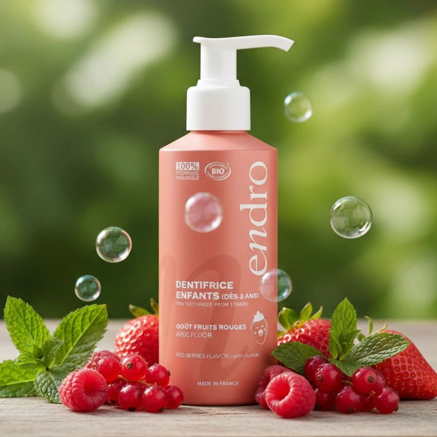 Un dentifrice pour enfants Endro, couleur corail et au goût de fruits rouges, est mis en scène dans un décor naturel.