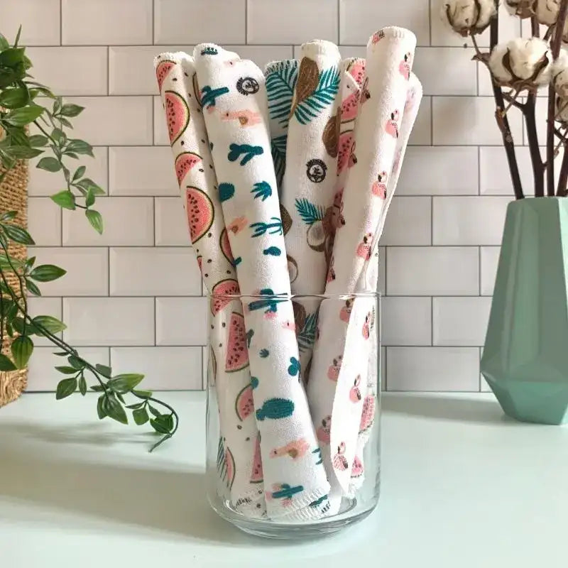 5 essuie-tout lavables Anotherway roulés et disposés côte à côte dans un vase en verre