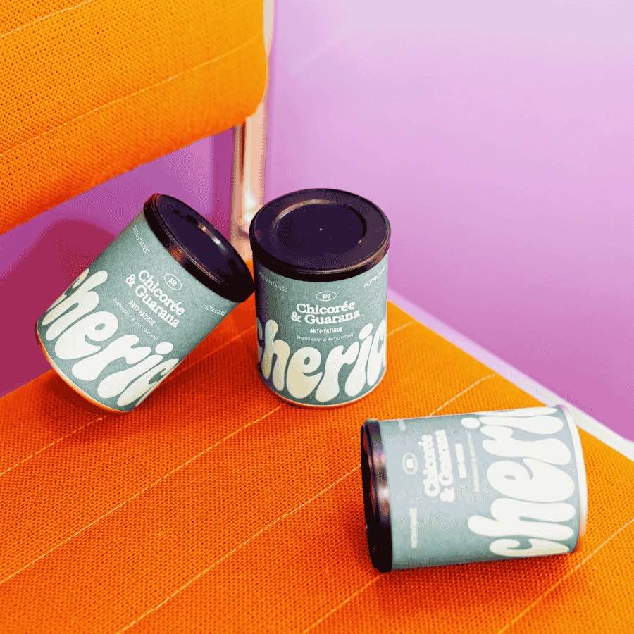 Trois boites de chicorée guarani sur une chaise orange.