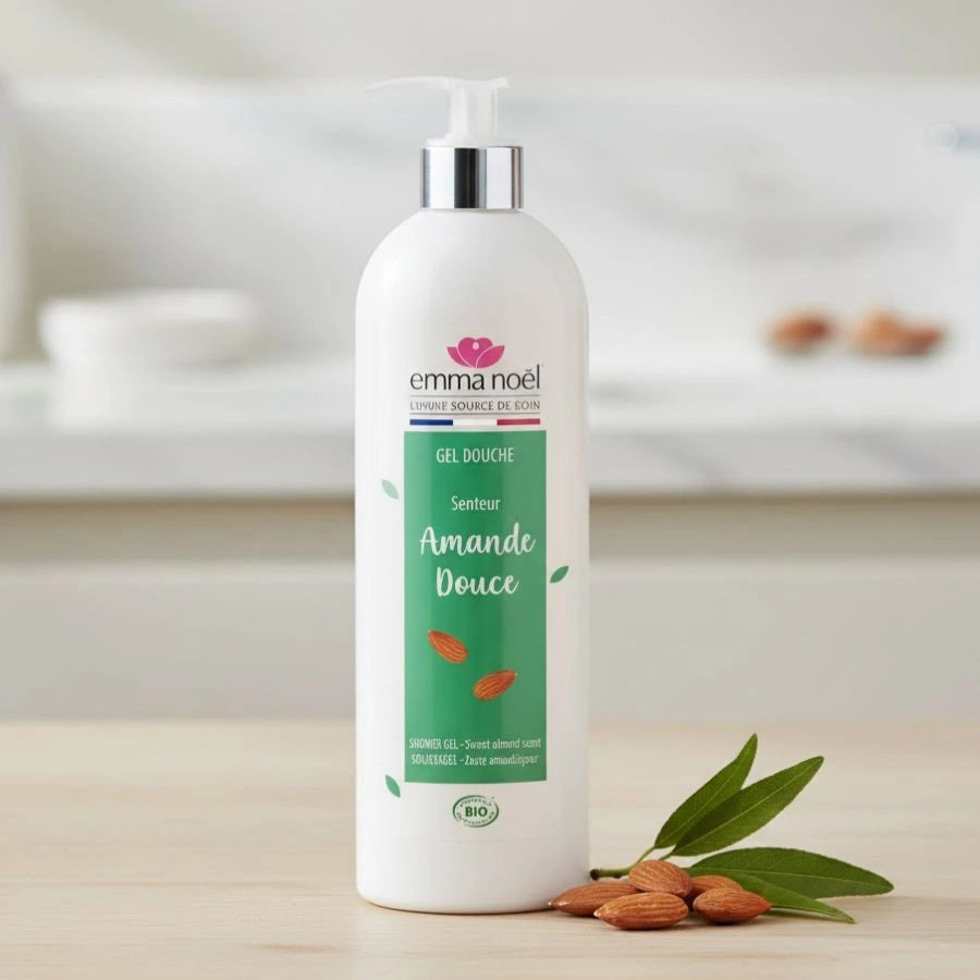Gel douche amande douce bio d'un format de 1L de la marque Emma Noël posé sur une table en bois et accompagné d'amande sur la droite.