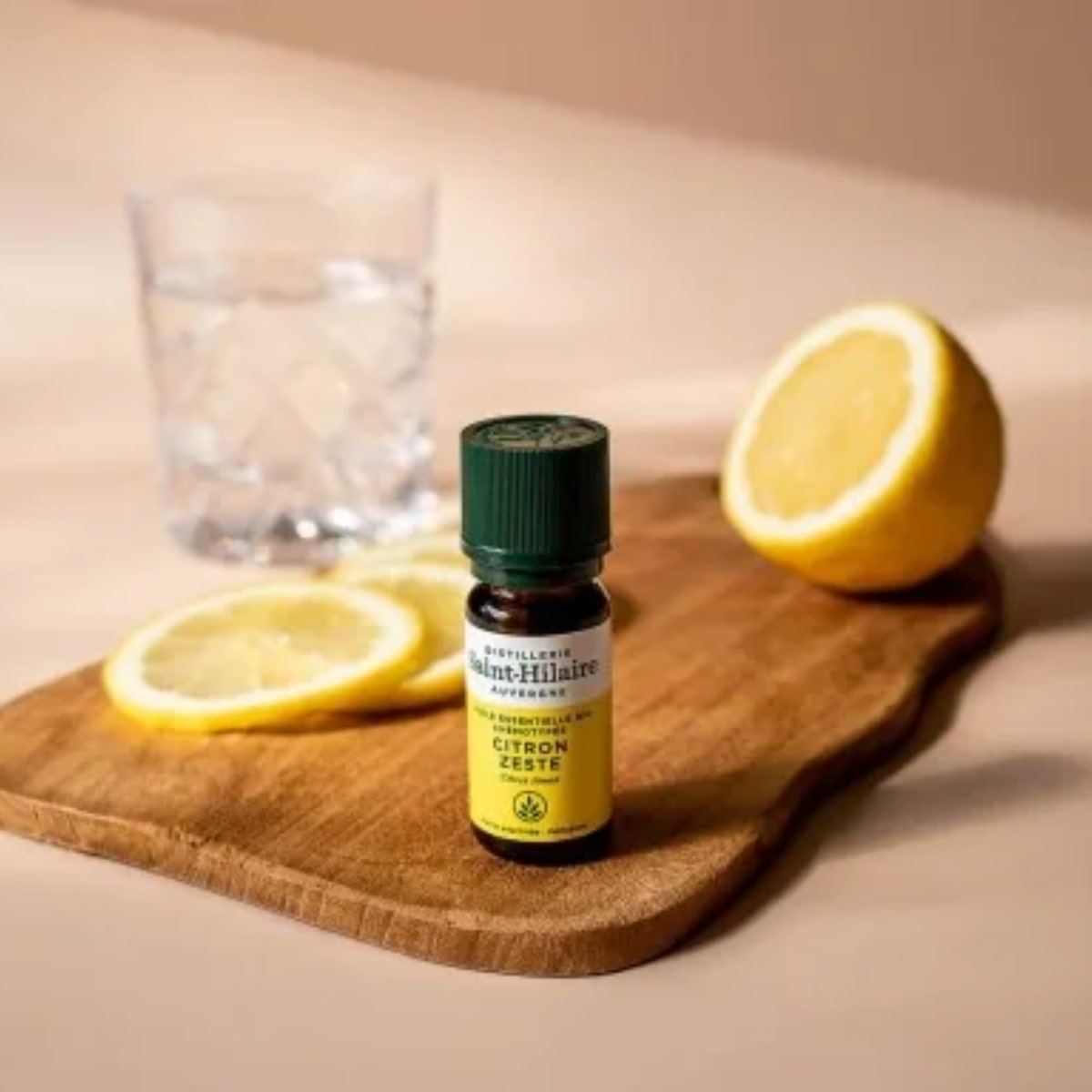 Un flacon de 10ml d'huile essentielle citron zeste de la distillerie Saint-Hilaire posé sur une planche en bois.