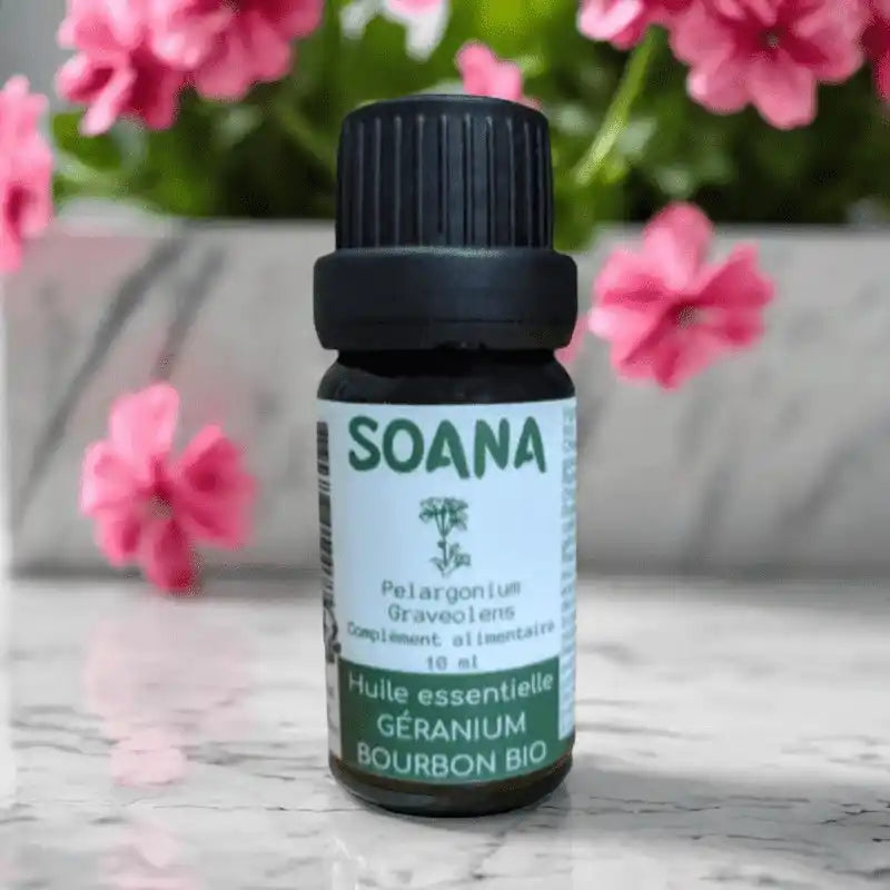 Flacon de 10 ml d'huile essentielle de Géranium Bourdon bio de la marque Soana sur fond fleuri 