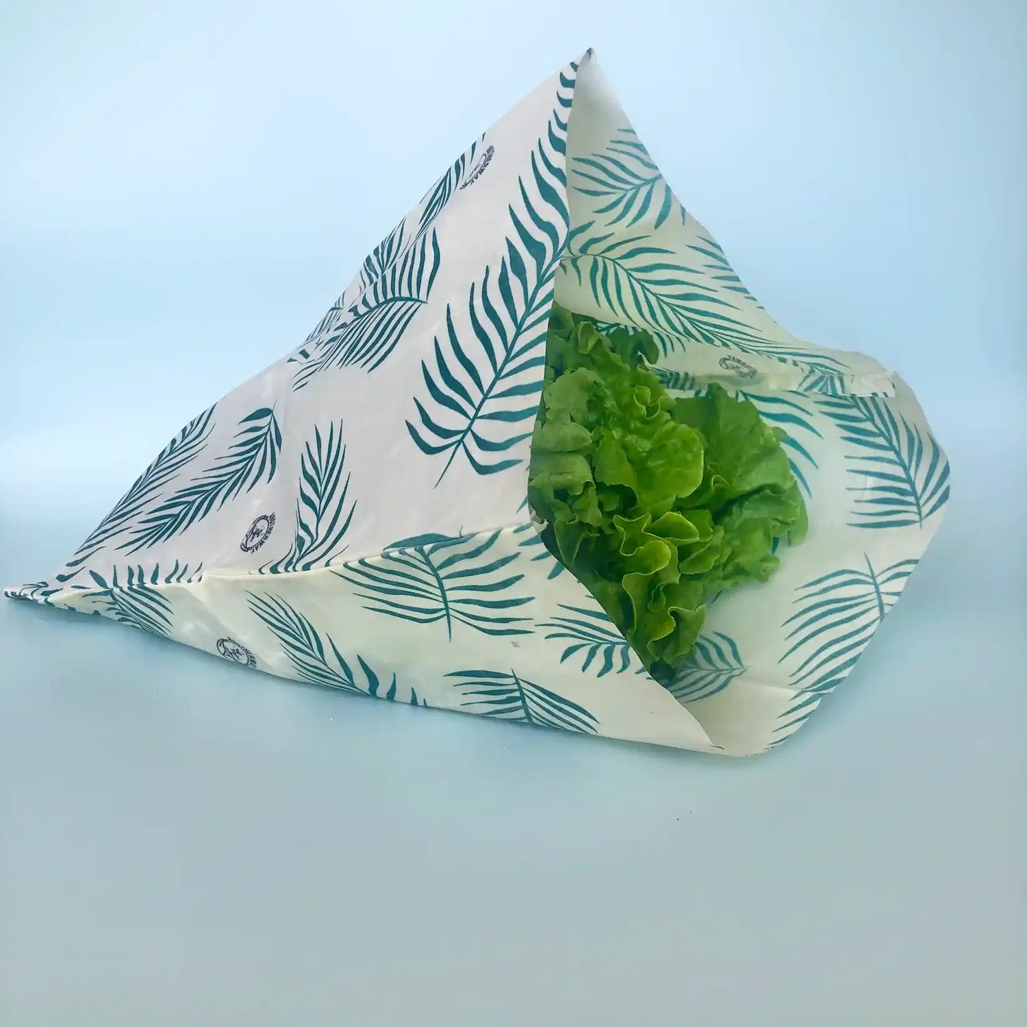Un Bee Wrap Sac Alimentaire Réutilisable Large Bio motif tropical , ouvert avec une salade dedans, de la marque Anotherway