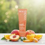 Le gommage visage éclat Endro est posé sur une surface en bois clair, entouré de tranches d'orange, de pêches coupées et de petites feuilles vertes.