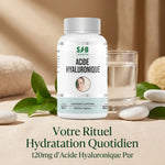 Bouteille Acide Hyaluronique 60 gélules SFB avec feuilles vertes et verre d'eau sur fond minimaliste wellness