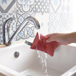 Une éponge lavables écologiques de la marque Anotherway en train d'être passée sous l'eau