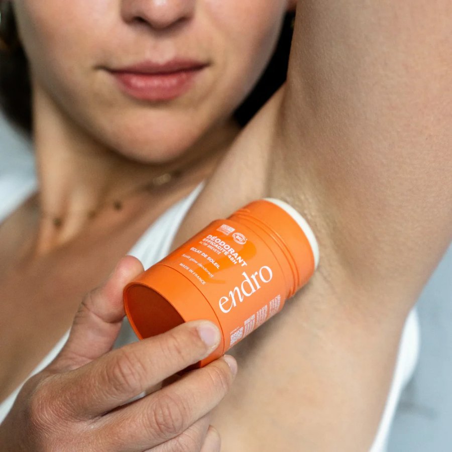 Personne appliquant un déodorant stick Endro sous l’aisselle, pour montrer son utilisation simple sur la peau.