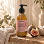 Flacon pompe ambré d'après-shampoing à l'huile de chanvre, lait de coco et figue, sur une étagère en bois avec serviette en lin et figue fraîche