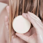 Une femme appliquant sur ses cheveux l'après-shampoing pour tout types de cheveux de la marque Endro 