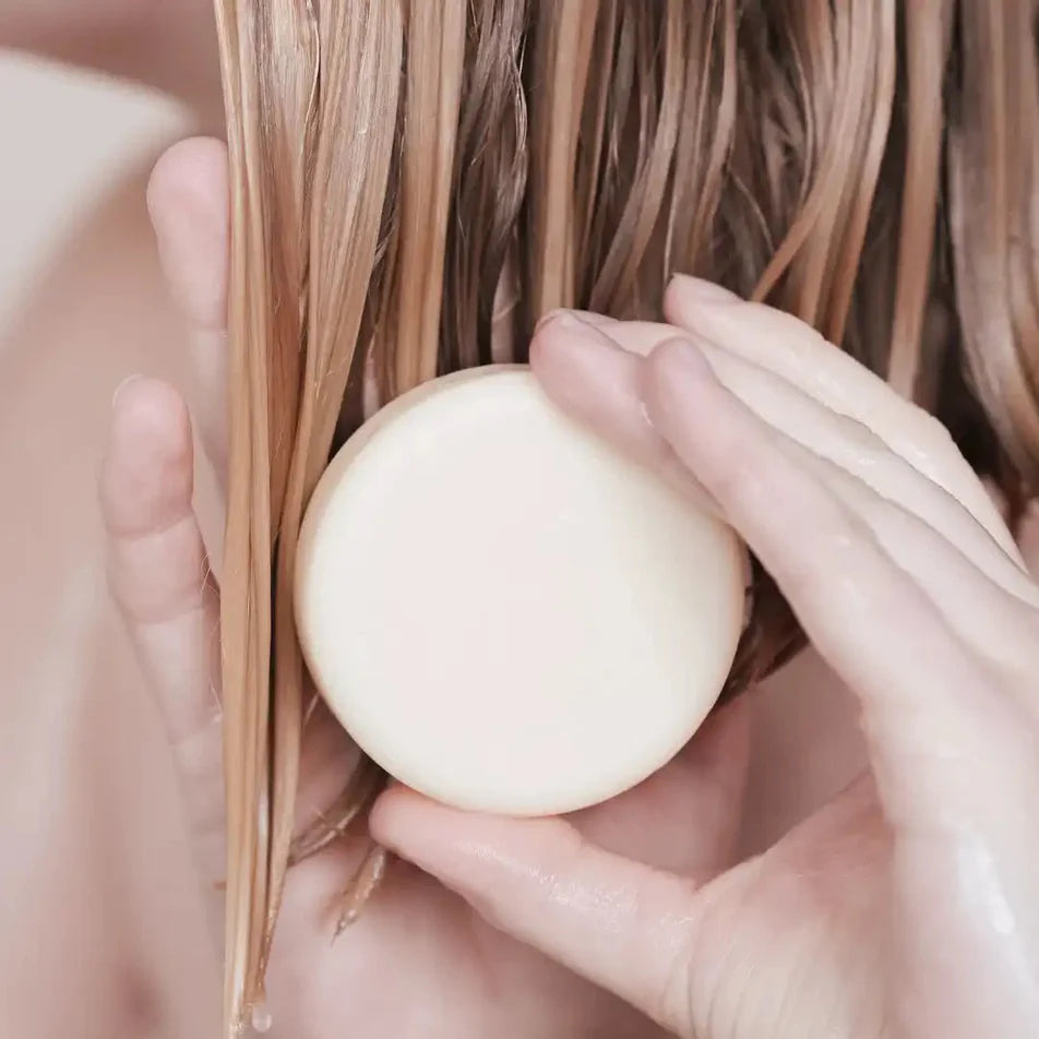Une femme appliquant sur ses cheveux l'après-shampoing pour tout types de cheveux de la marque Endro 