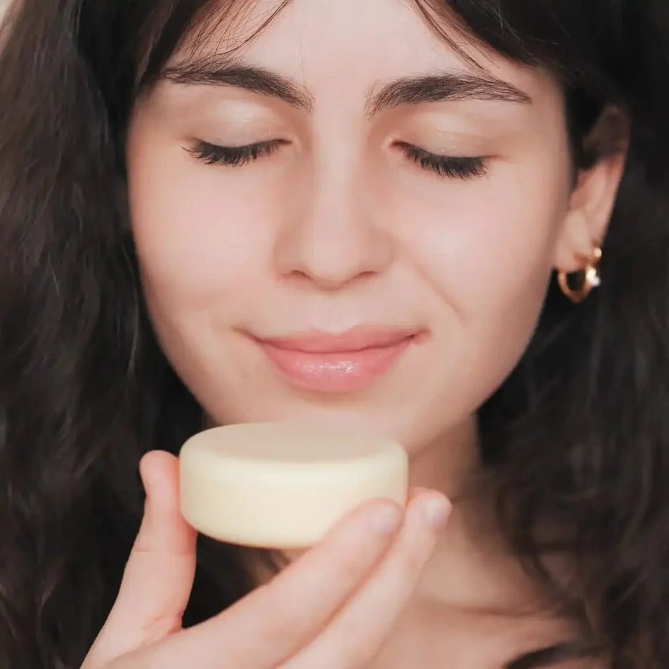 Une femme en train de sentir un après-shampoing pour tout types de cheveux de la marque Endro