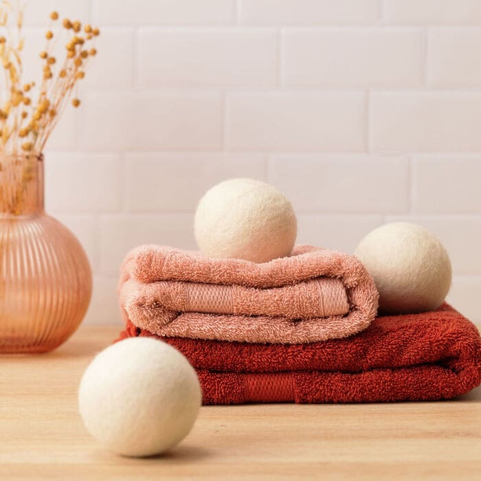 3 Balles de séchage en laine Pimpant posées sur une serviette